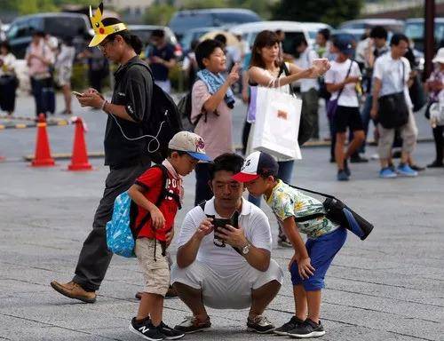 2017年8月9日，在日本横滨，人们用手机玩游戏。（新华社/路透）