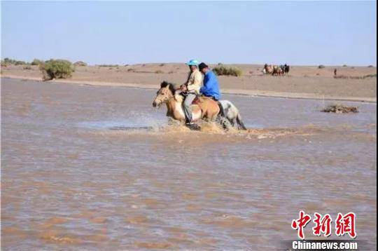 图为当地牧民骑马过河。额济纳旗委宣传部供图 摄