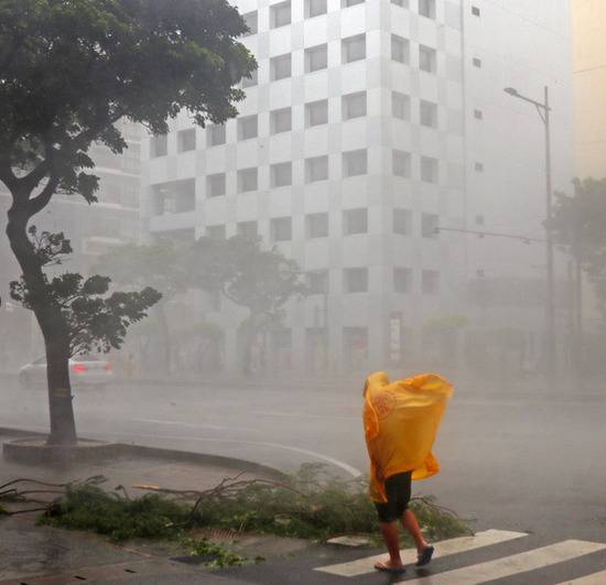 在风雨中行进的那霸市路人（图片来源：朝日新闻）