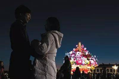 晨光微曦中对视的情侣，他们的身后是祝福祖国的花篮。新京报实习生陈婉婷摄