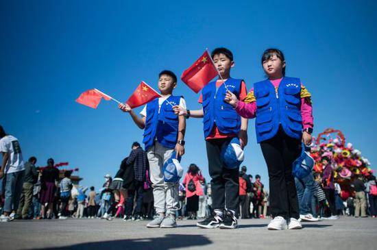 10月1日，孩子们在天安门广场挥舞国旗庆祝国庆。（法新社）