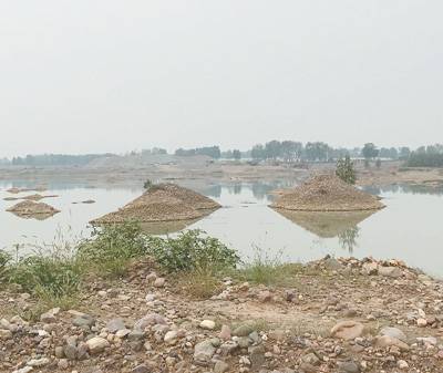 沙河河道被砂石运输路截断。河道内有很多砂石堆。本报记者张洋摄