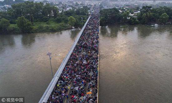 当地时间10月20日，墨西哥与危地马拉边境，数千名中美洲移民在危地马拉-墨西哥国际大桥上等待开放关卡，被警察拦截，一些移民则选择自制小艇穿越危地马拉与墨西哥之间的天然屏障——苏伊赛特河。@视觉中国