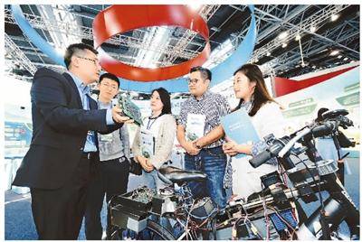 10月8日，北京一家企业工作人员（左一）正在2018全国双创周北京会场展示自主研发的类脑芯片，它具有高计算力、高多任务并行度和较低功耗等优点。本报记者贺勇摄