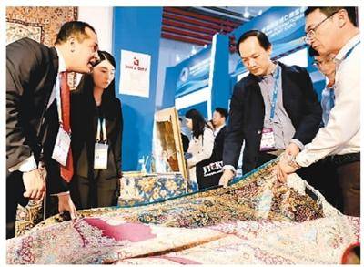 11月5日，一名来自伊朗的地毯参展商（左）向参观者介绍自己的产品。