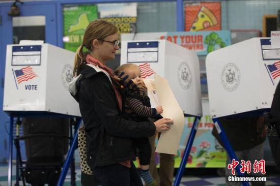 当地时间11月6日，美国2018年中期选举投票日，纽约一位母亲带着幼子在位于布朗克斯区的一处投票站投票。中新社记者廖攀摄