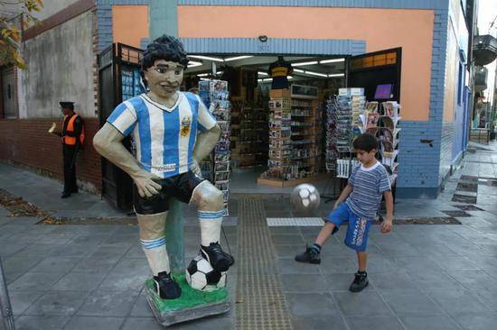 博卡区一名孩子在马拉多纳雕塑旁踢足球
