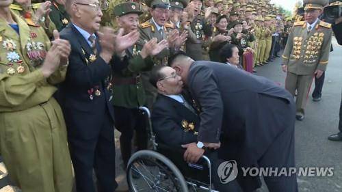 今年7月，金正恩俯身与参加老兵大会的金铁万交谈。（韩联社）