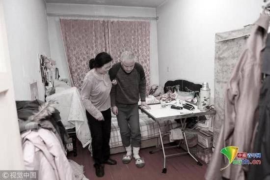 2018年11月22日，辽宁丹东，在出租屋内，袁东方的母亲正在搀扶着老伴儿锻炼身体。魏建顺/视觉中国