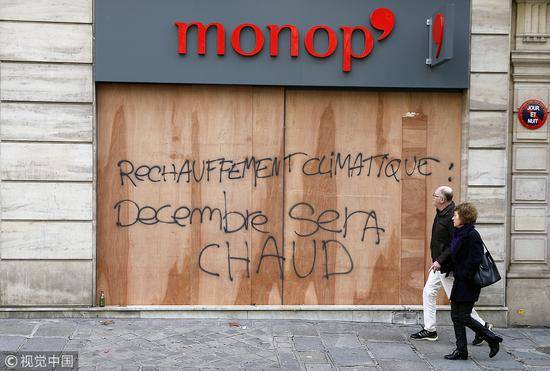 法国一小超市用胶合板保护橱窗，板子上还被抗议者写上“气候变暖了！十二月会很‘热’！”的语句。（图源：视觉中国）