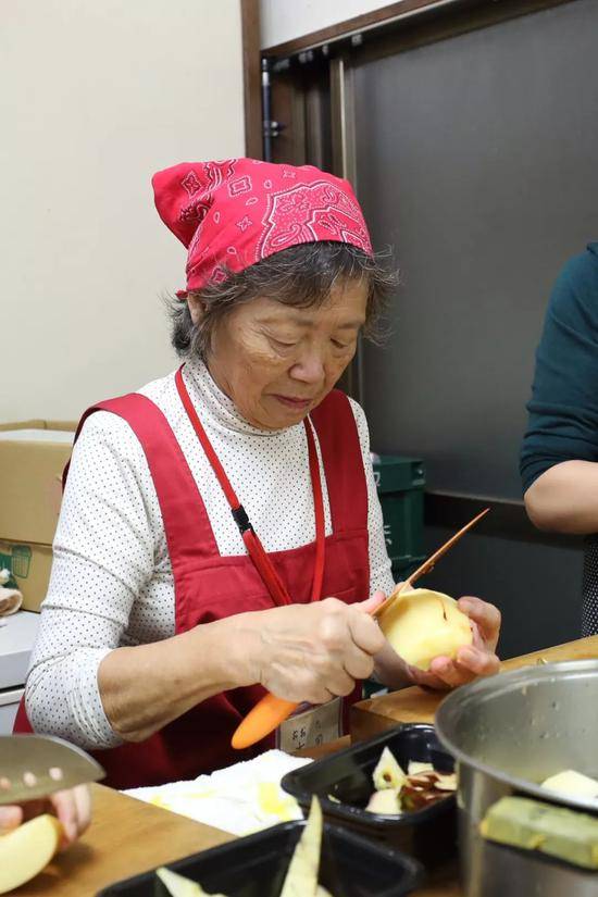 老奶奶在食堂厨房里削苹果。