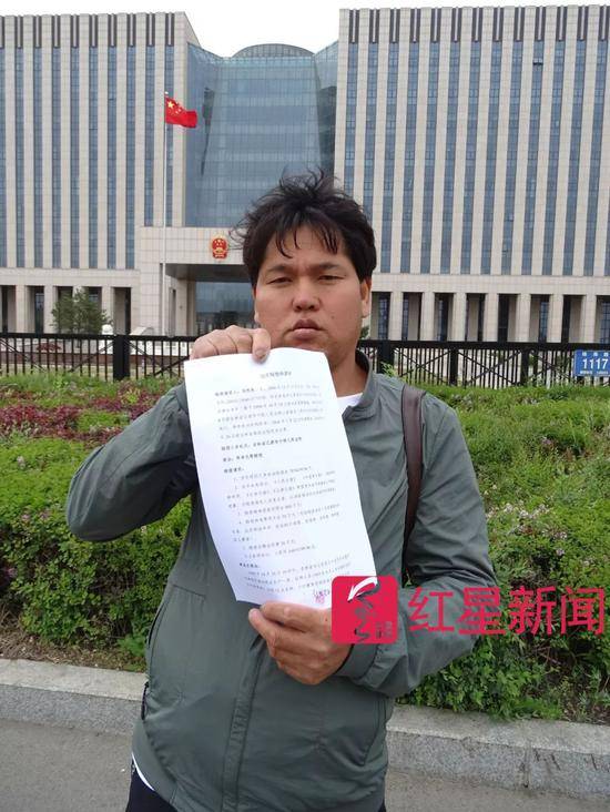 ▲去年5月23日，刘忠林在吉林省高院门前，手拿国家赔偿申请书受访者供图