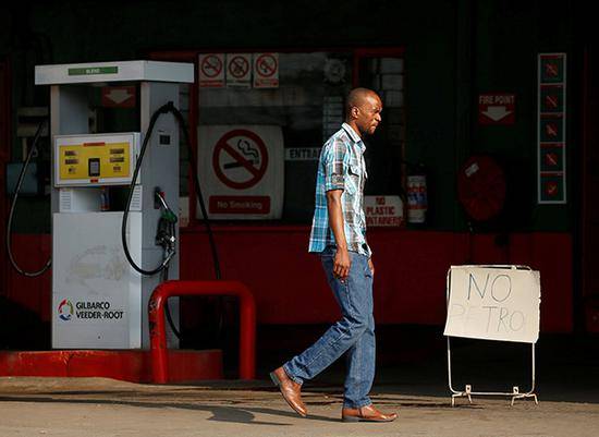 行人经过津巴布韦哈拉雷一个加油站。视觉中国资料