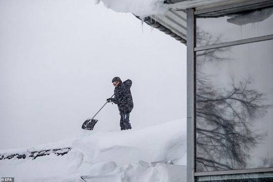 德国，一名男子正在清扫屋顶积雪。