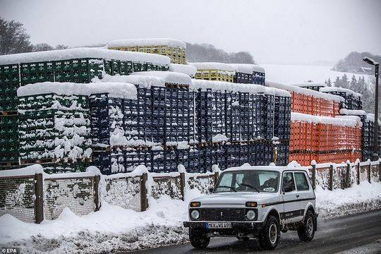 德国，一辆汽车经过被大雪覆盖的啤酒箱。