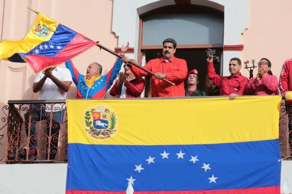 1月23日，在委内瑞拉加拉加斯，委总统马杜罗（中）在参加群众集会时挥舞国旗。新华社发
