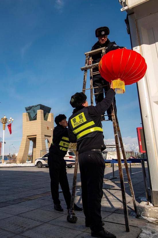 除夕当天，新疆霍尔果斯口岸边境派出所民警正在中哈霍尔果斯国际边境合作中心中方区域内悬挂红灯笼。郭炜摄