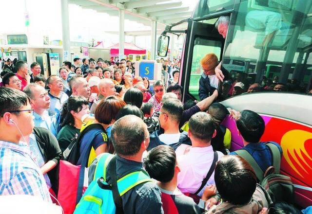 经港珠澳大桥抵达香港口岸的众多内地游客在巴士站候车，其中前往铜锣湾的大巴车门前挤满了旅客图自中新社