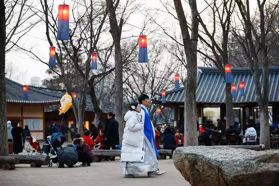 2月5日，一对年轻情侣身着韩服在韩国京畿道龙仁市的韩国民俗村参观。当日是农历新年第一天，不少韩国民众身着韩服来到韩国民俗村体验年俗。韩国民俗村有传统住宅260余座，再现了朝鲜半岛传统社会的风貌。在节假日期间安排丰富多彩的民俗游戏，供游客体验。新华社记者王婧嫱摄