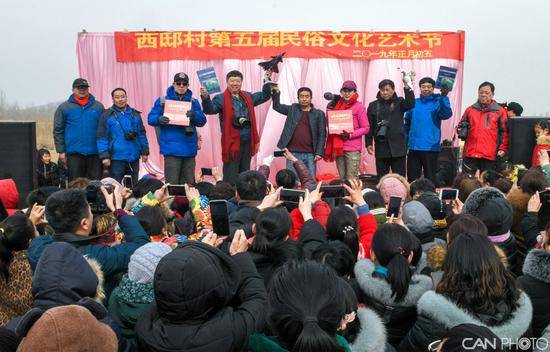 航空摄影家牟健为向西邸村无人机队发起人张启龙，赠送国产先进的歼20战机模型，表达了航空摄影家们对西邸村群众和无人机小组的祝福！