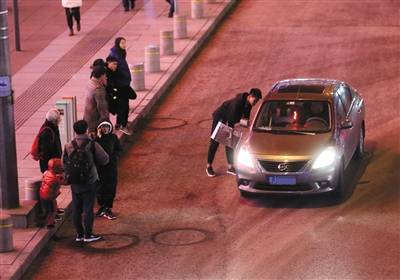 2月15日晚，西单一些乘客站在马路上等车，一辆“黑车”司机正在和乘客“讨价还价”