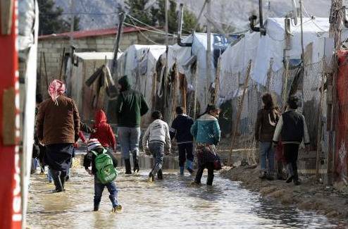 资料图片：1月17日，在黎巴嫩贝卡谷地的一处叙利亚难民营，人们在积水中行走。（法新社）