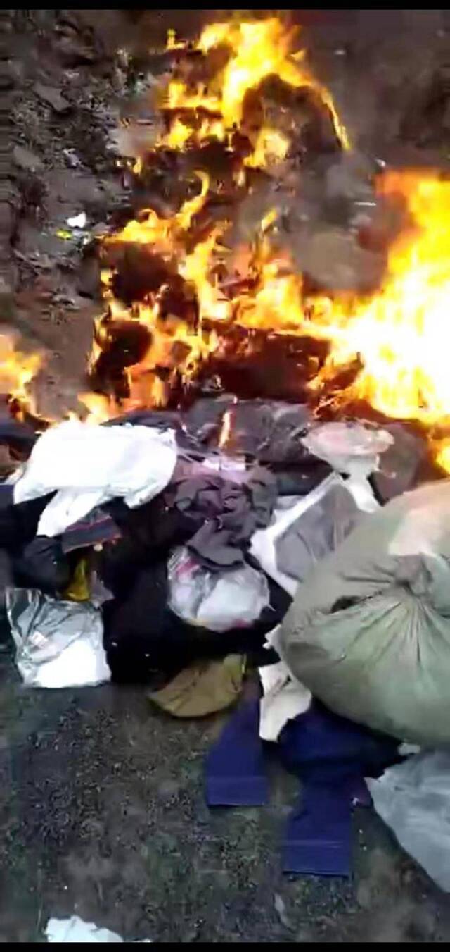 视频显示，大批袋装衣服正在被烧毁。视频截图