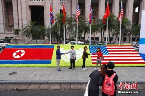当地时间2月26日，越南首都河内，民众在“金特会”造型花坛前握手合影。朝美领导人第二次会晤将于2月27日-28日在越南首都河内举行。中新社记者富田摄