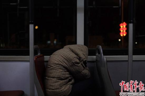 深夜1点的公车上，一名青年和衣蜷缩在座椅上。中国青年报·中青在线记者郑萍萍摄