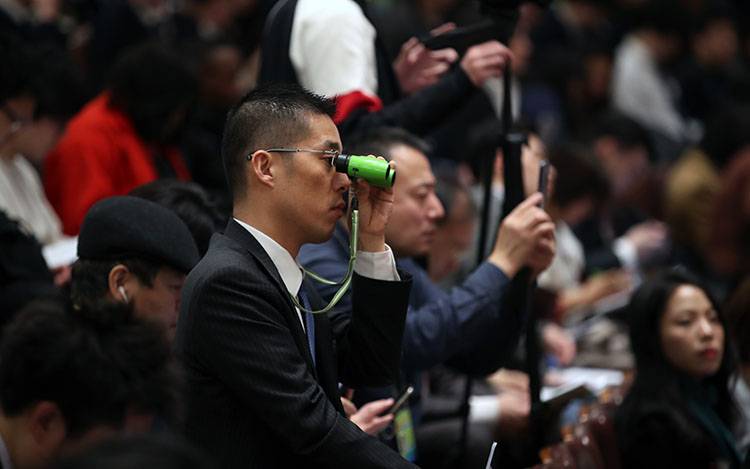 2019年3月5日，人民大会堂，十三届全国人大二次会议开幕。一位记者拿着望远镜观看会场。新京报记者薛珺摄