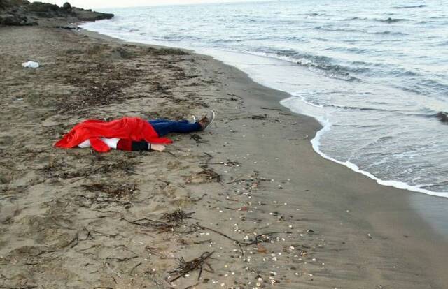 沙滩上躺着另一具年轻难民的尸体