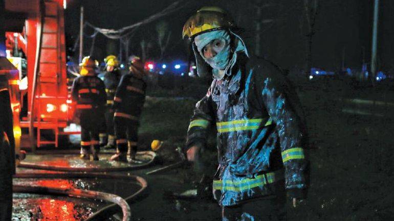 3月22日，在前线参加灭火救援的消防员拍打掉身上的泡沫。新京报记者彭子洋摄