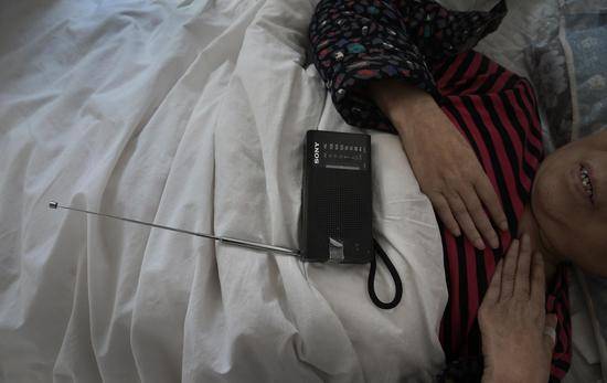 2019年3月14日，北京松堂医院，一位卧床的老人在听收音机。新京报记者尹亚飞摄