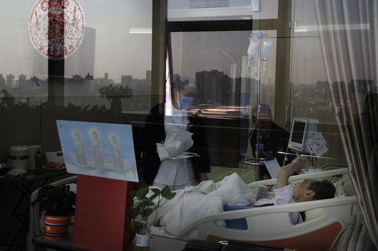 2018年10月16日，北京大学首钢医院安宁疗护中心，一间病房里，患病男子躺在病床上，护士正在询问他今天身体的情况，他的老伴儿坐在一边。新京报记者尹亚飞摄