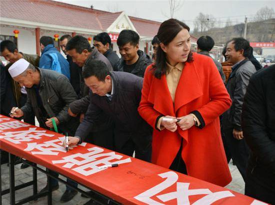 马新娟（着红衣者）在脱贫攻坚活动上签名（资料照片）。新华社发