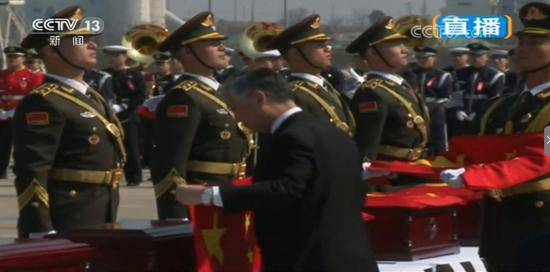 在韩国的烈士遗骸交接仪式上，我驻韩大使为棺椁披盖国旗。（央视截图）