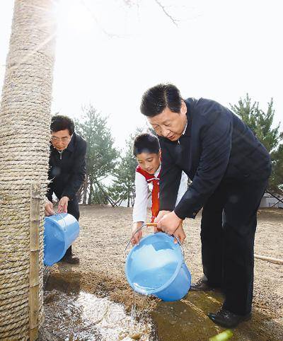 2013年4月2日，习近平同少先队员一起给刚栽下的银杏树浇水。新华社记者鞠鹏摄