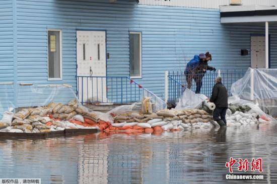 当地时间4月20日，加拿大魁北克省圣玛丽市，暴雨造成Chaudiere河河水决堤，引发洪水。图为当地民众在摆放沙袋抵御洪水。