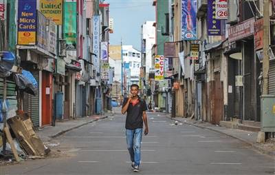 一名男子走在空荡荡的街道上，那里的商店在实施宵禁后关闭。