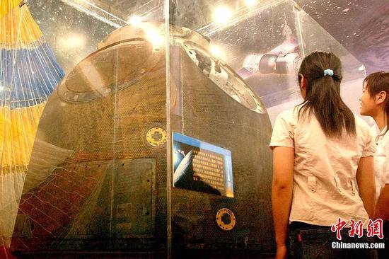 资料图：2005年5月27日，两个女孩在河南科技馆观看“神舟一号”飞船。中新社发慎重摄