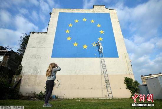 资料图：当地时间2017年5月7日，英国多佛，街头艺术家班克西创作了一幅画，画面中一名工人正从欧盟12星旗帜上抹掉一颗星，寓意着英国将脱离欧盟。