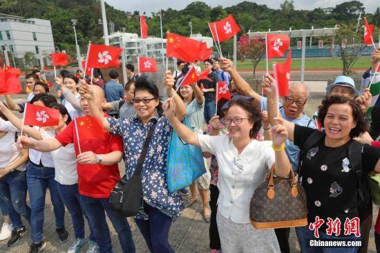 4月30日，香港市民挥舞中华人民共和国国旗和香港特区区旗，欢迎海军舰艇编队到来。当日，由导弹驱逐舰海口舰、导弹护卫舰黄山舰组成中国人民解放军海军舰艇编队，在执行完海军成立70周年阅舰任务返航归建途中靠泊香港，受到香港特区政府和市民热烈欢迎。中新社记者谢光磊摄