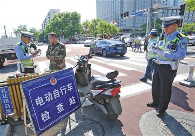 5月1日，宣武门路口，交警正在对一位有电动自行车临时标识但未悬挂的车主进行处罚。新京报记者王贵彬摄