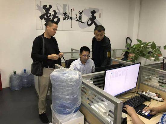 两位刑警大队民警在深圳福道文化传播有限公司技术部里调查嫌疑人。