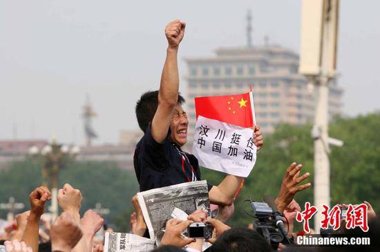 2008年5月19日，北京天安门广场上的民众为地震遇难者默哀，一位男子高举右手为家乡加油。（中新社记者富田摄）