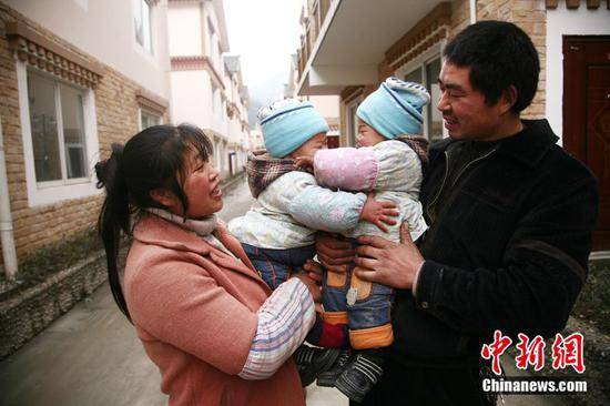 2011年1月28日，震中映秀镇张家坪村村民搬进了新家，再生育家庭抱着双胞胎拍摄合影。（中新社记者张浪摄）
