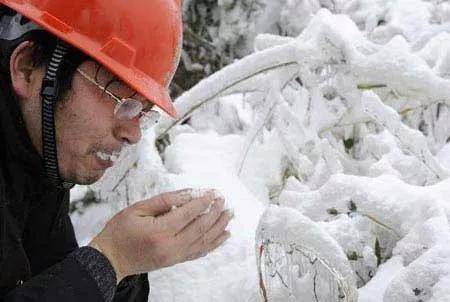 2008年2月2日，一名电力抢险队队员在湖北省通山县抢险现场吃雪解渴。