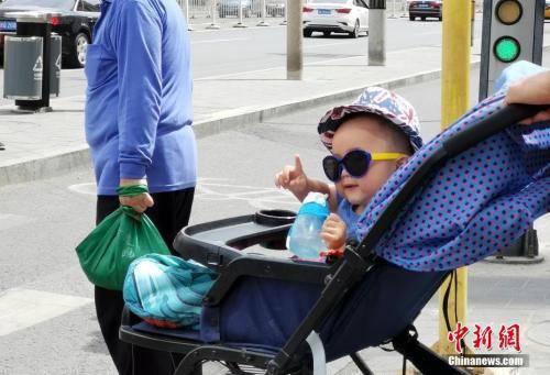 5月22日，北京街头一名孩子在婴儿车中戴着墨镜。中新社记者杜洋摄