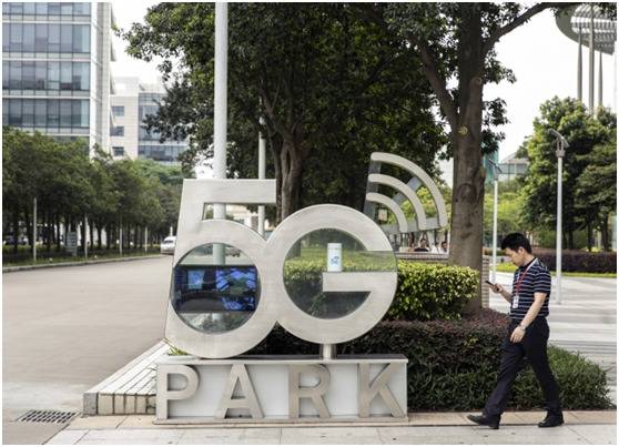 一名员工走过华为5G公园标牌，图源：彭博社