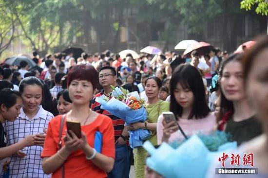 资料图：家长捧着鲜花在考场外等候孩子出现。王以照摄